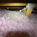 A pile of pink foam in the middle of an attic.