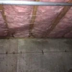 A room with pink insulation and concrete floor.