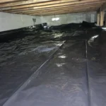 A black tarp covering the floor of an unfinished room.
